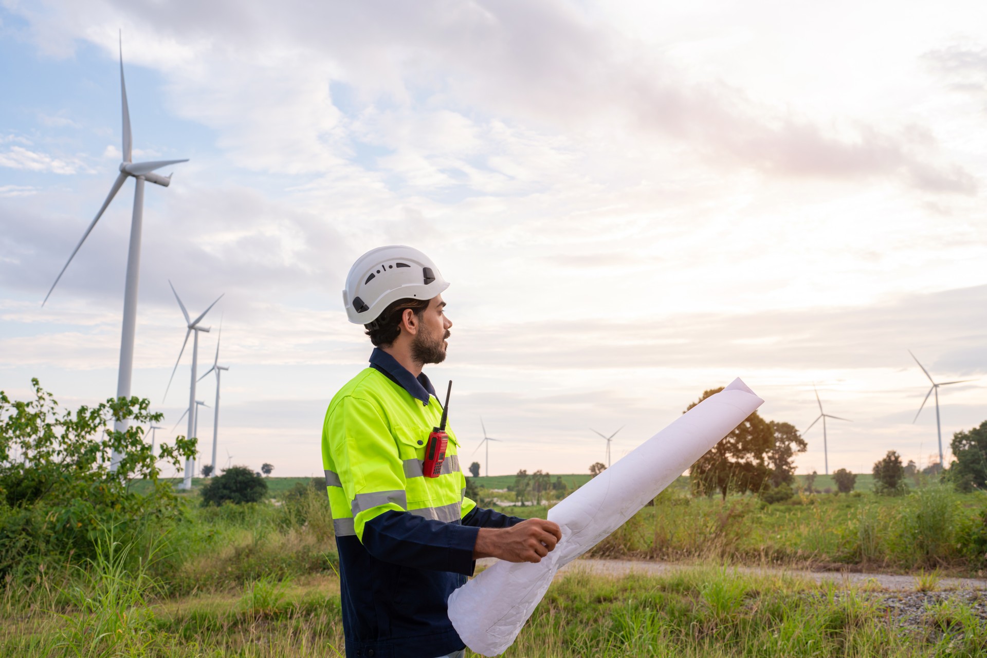 Engineer wearing uniform inspection and survey work in wind turbine farms rotation to generate electricity energy.